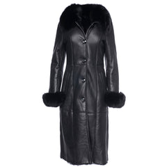 A full-length black shearling sheepskin coat with fox fur trim on the cuffs and collar, featuring a buttoned closure and two functional front pockets.