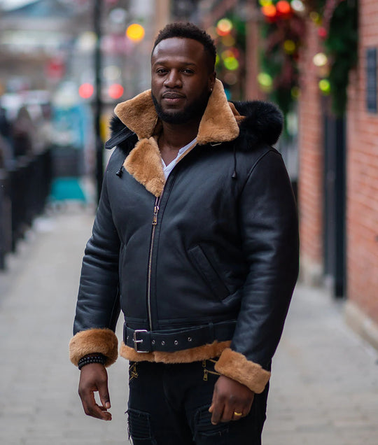 Side view of Jean's B3 Bomber Aviator Shearling Jacket worn by a man with a hoodie on street, highlighting the distressed black leather body and the tan shearling lining. 