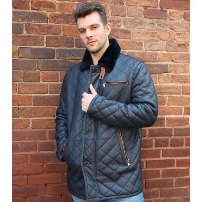 Man wearing a quilted jacket with fur collar against a brick wall
