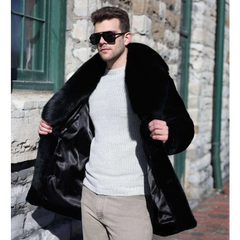 Man wearing a black fur coat and sunglasses against a stone building background