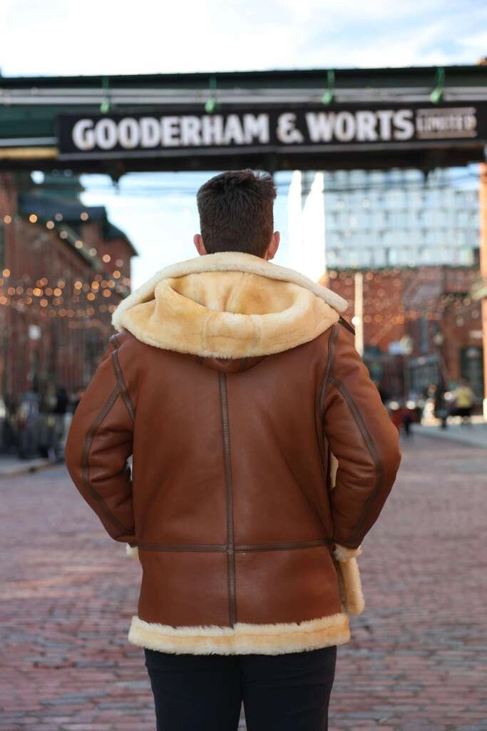 Person wearing a brown leather jacket with fur lining in front of Gooderham & Worts sign.