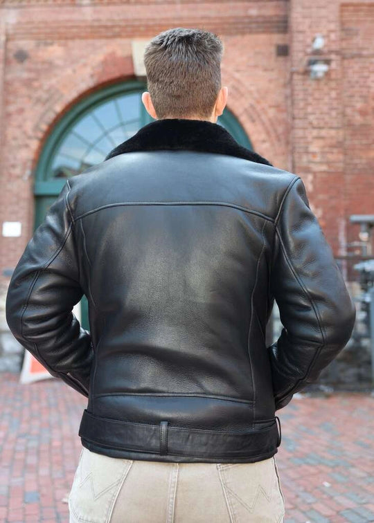 Person wearing Black on Black Belted Shearling Leather Biker Jacket with a fur collar in front of a brick building.