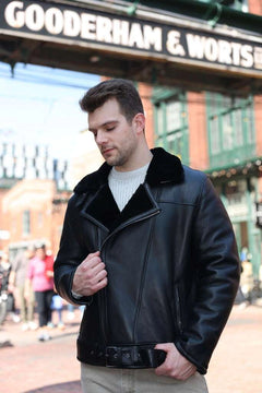 Man wearing a Black on Black Belted Shearling Leather Biker Jacket in front of a building with 'Gooderham & Worts' sign.
