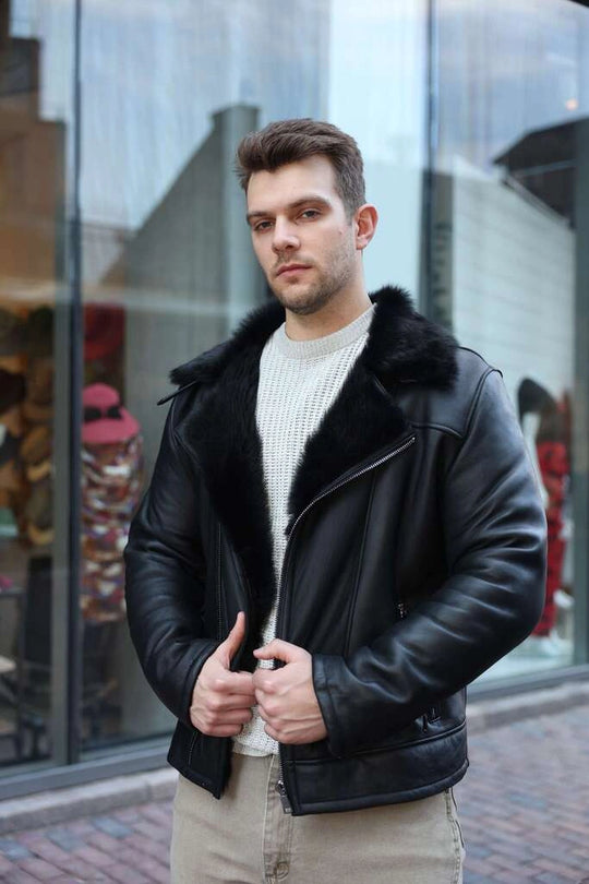 Man wearing a Carter's Toscana Shearling Leather Biker Jacket with fur collar standing in front of a glass building.