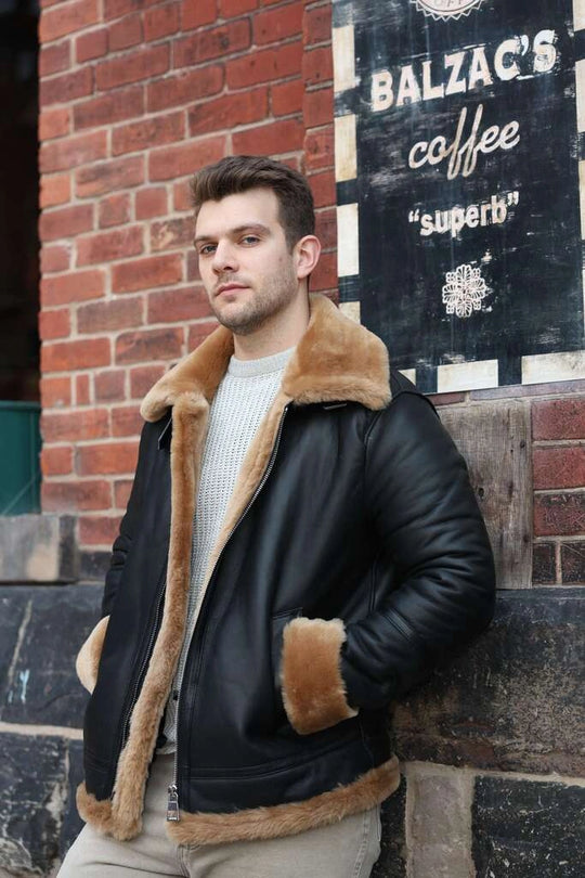 Man wearing Classic Ginger Brown B3 Bomber Aviator Shearling Jacket with brown fur lining leaning against a brick wall with 'Balzac's Coffee' sign.
