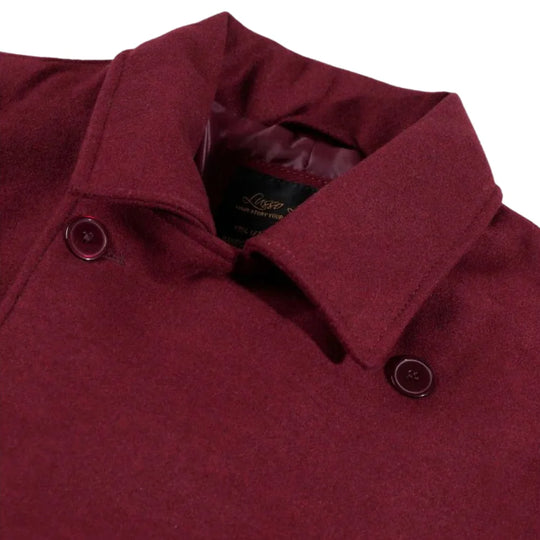 Close-up of a burgundy coat with a collar and buttons on a white background