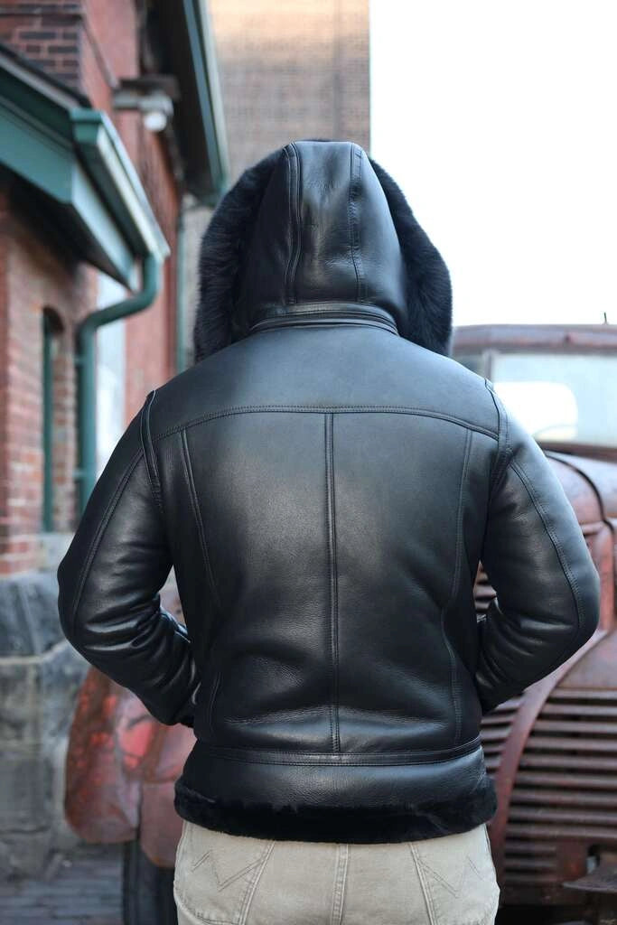 Person wearing Felix black bomber shearling jacket with hood outdoors.
