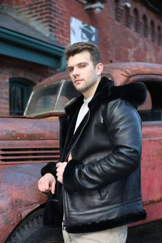 Man wearing Felix black bomber shearling jacket with fur trim standing in front of an old red truck.