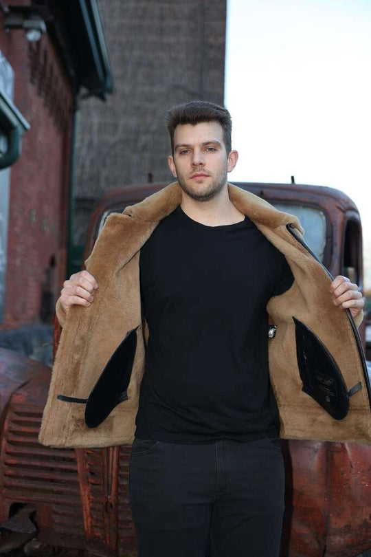 Man showcasing interior of Graysen black Aviator bomber shearling jacket over a black shirt in front of an old truck.