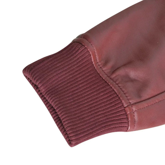 Detailed close-up of the burgundy ribbed knit cuff on a leather bomber jacket, highlighting the elasticized texture and durable seam work on white background.
