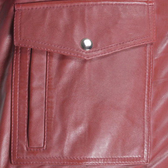Close-up of a burgundy leather jacket pocket with a button.