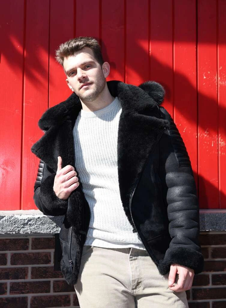 Man wearing Lucas Black Aviator Bomber Shearling Jacket with Hoodie against a red wall